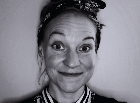 Smiling woman with a bandana headband looking at the camera (black-and-white portrait).