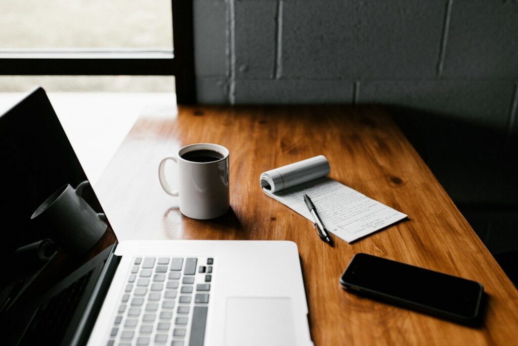 . - Aktivitus MacBook Pro, white ceramic mug,and black smartphone on table